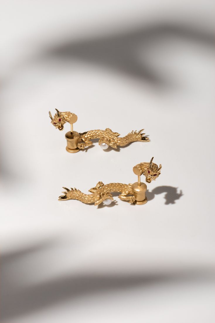 Gold dragon earrings with soft shadows, jewellery product photography